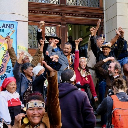 Members of the Goringhaicona and others opposing the River Club development celebrate the dismissal of an urgent application to depose Tauriq Jenkins (centre) as supreme high commissioner of the Goringhaicona Khoi Khoin Indigenous Traditional Council. Together with the Observatory Civic Association, the council has led litigation against the development. Photo by GroundUp, Steve Kretzmann